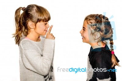 Little Girl Telling Her Sister To Shut Up With Her Finger On The Mouth. A Gesture Of Silence . Closeup-isolated On White Background Stock Photo