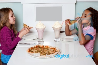 Little Girls Enjoying Pizza In A Restaurant Stock Photo