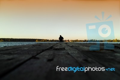 Lone Man On Pier Orange Sunset Stock Photo