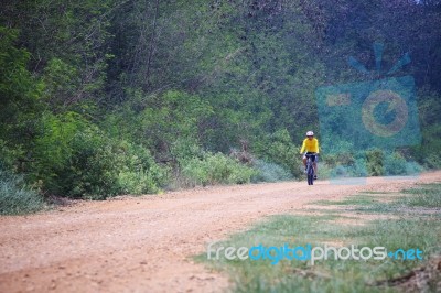 Lonely Cyclist Biking Mountain Bike On Dusty Road Stock Photo