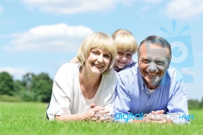 Lovable Family Of Three Lying In The Park Stock Photo