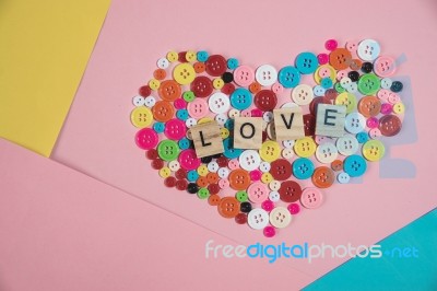 Love Word Written On Wooden Block Placed On Colourful Button In Stock Photo