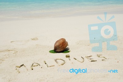 Maldives Written In A Sandy Tropical Beach And Coconut Fruit Stock Photo