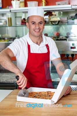 Male Chef Using Pizza Cutter Stock Photo