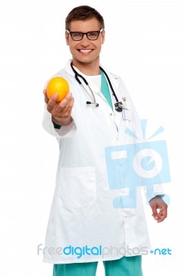 Male Doctor Showing Orange Fruit Stock Photo