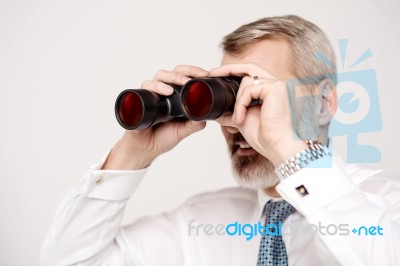 Male Execuitve Peers Through Binoculars Stock Photo