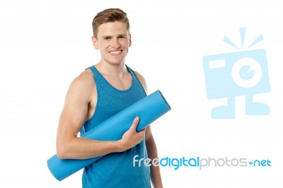 Male Gym Instructor Holding Blue Mat Stock Photo