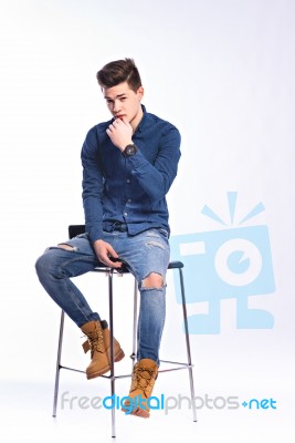 Male Model In Denim Jeans Sitting On A Chair . Studio Shoot Stock Photo