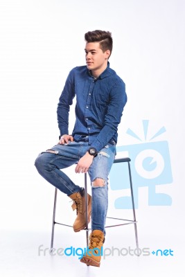 Male Model In Denim Jeans Sitting On A Chair . Studio Shoot Stock Photo