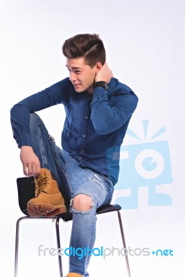 Male Model In Denim Jeans Sitting On A Chair . Studio Shoot Stock Photo