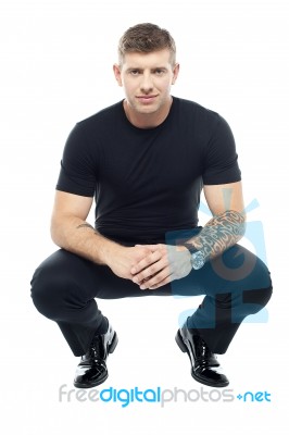 Male Squatting On Floor Stock Photo