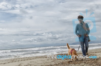 Man And Dog Walking On The Beach Stock Photo