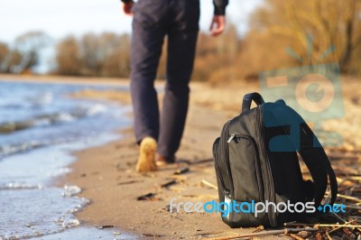 Man Left His Backpack And Walking On The Beach Stock Photo