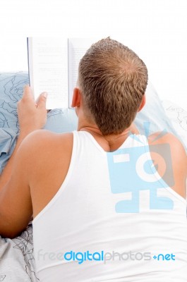 Man Reading Book While Resting Stock Photo