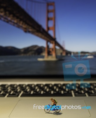 Man Riding Bicycle Model On Laptop With Golden Gate Bridge Background Stock Photo