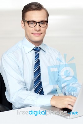 Man Sitting On Chair Using Laptop In Office Stock Photo