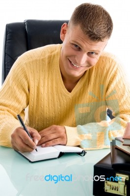 Man Smiling While Writing Stock Photo