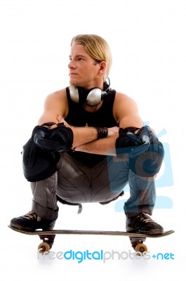 Man squatting On Skate Board Stock Photo