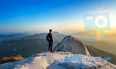 Man Stands On The Peak Of Stone In Bukhansan National Park,seoul In South Korea And Watching To Sunrise. Beautiful Moment The Miracle Of Nature Stock Photo