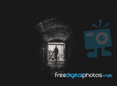 Man Walking Toward The Light At The End Of A Tunnel Stock Photo