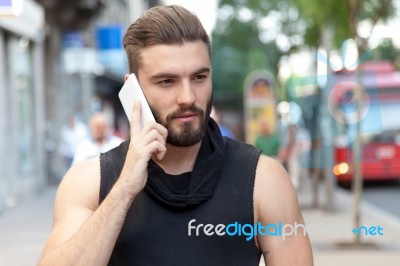 Man With A Beard Talking With Your Smart Phone On The Street Stock Photo