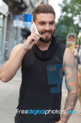 Man With A Beard Talking With Your Smart Phone On The Street Stock Photo