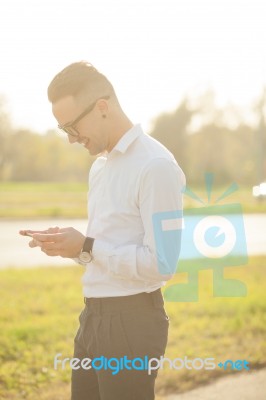 Man With Glasses Texting On Mobile Phone In Hands Stock Photo