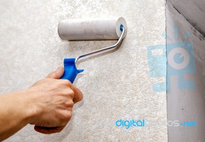 Man's Hand Smoothing The Wallpaper With A Roller Closeup Stock Photo