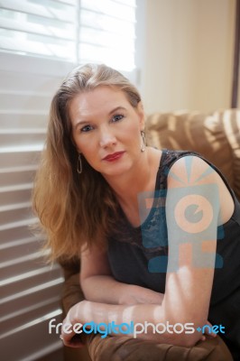 Mature Blonde Leaning On Chair Arm In Portrait Stock Photo