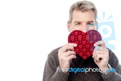 Mature Man Holding Heart Shaped Gift Box Stock Photo