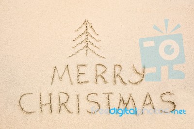 Merry Christmas Inscription On Wet Yellow Beach Sand Stock Photo