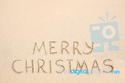 Merry Christmas Inscription On Wet Yellow Beach Sand Stock Photo