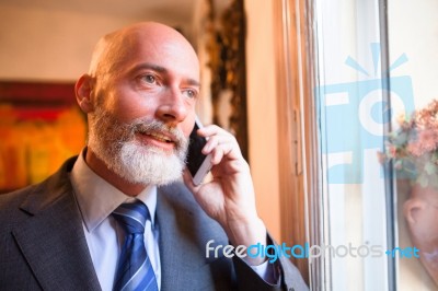 Middle-aged Businessman Listening On Smartphone At Home Stock Photo