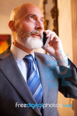 Middle-aged Businessman Listening On Smartphone At Home Stock Photo