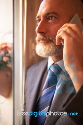 Middle-aged Businessman Listening On Smartphone At Home Stock Photo