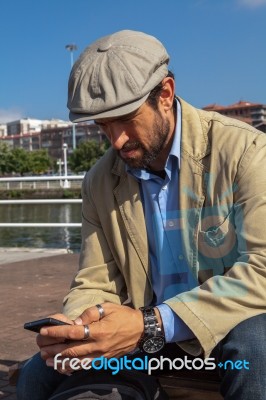 Middle-aged Man With Irish Beret Looking At His Smartphone Stock Photo