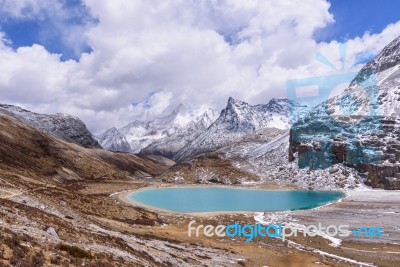 Milk Lake On The Snow Mountains With Clouds And Sky In Yading, China Stock Photo