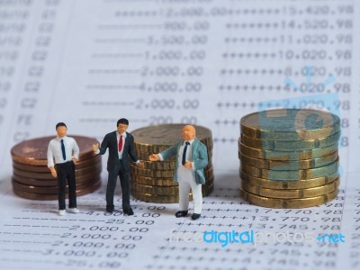 Miniature Businessman Stand On Book Bank, Near Pile Of Coins. Bu… Stock Photo