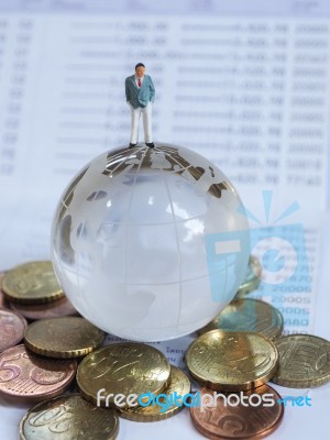 Miniature Businessman Stand On Globe Of Glass, Euro Coins And Bo… Stock Photo