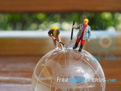 Miniature Businessman Stand On Globe Of Glass With Wooden Backgr… Stock Photo