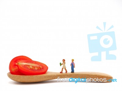 Miniature Children Standing On Fresh Grape Or Cherry Tomato With… Stock Photo