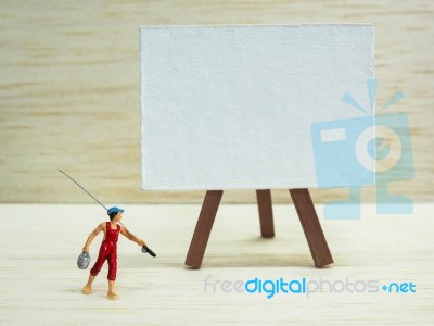 Miniature Little Boy Standing Near An Easel On Wooden Background… Stock Photo