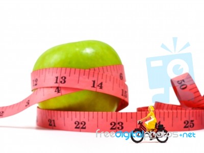 Miniature Woman Riding Bicycle Near Green Apple And Measuring Ta… Stock Photo