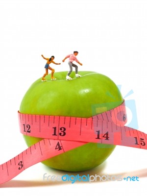 Miniature Woman Skating On Green Apple And Measuring Tape , Thin… Stock Photo