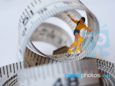 Miniature Woman Skating On Measuring Tape, Thinking Of Weight Lo… Stock Photo