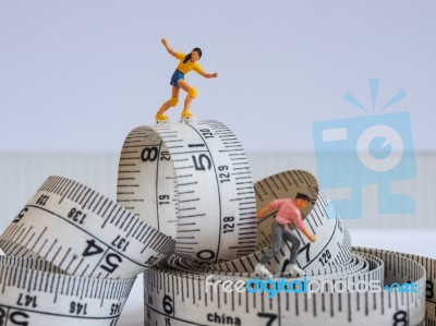 Miniature Woman Skating On Measuring Tape, Thinking Of Weight Lo… Stock Photo