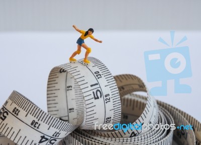 Miniature Woman Skating On Measuring Tape, Thinking Of Weight Lo… Stock Photo