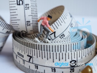 Miniature Woman Skating On Measuring Tape, Thinking Of Weight Lo… Stock Photo