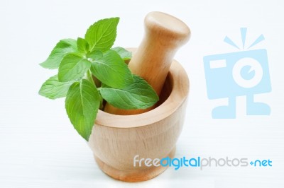 Mint Leaves In Wooden Mortar On White Wooden Background Stock Photo