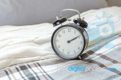 Modern Black Alarm Clock On Bed In Bedroom Stock Photo